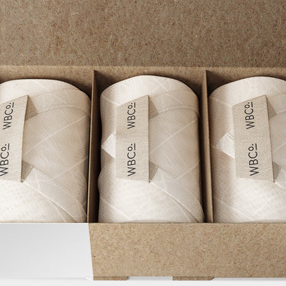 Three rolled bamboo cloths placed side by side in an open cardboard box, with the brand label 'WBCO' visible on each roll. face wipe