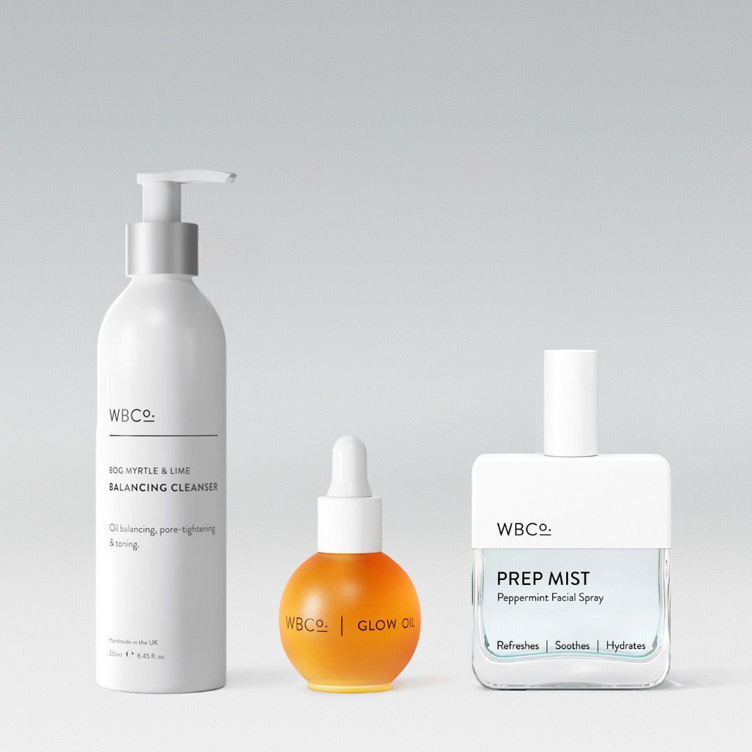 A set of three skincare products from WBCo, including a balancing cleanser in a white pump bottle, a glow oil in a round dropper bottle, and a prep mist in a spray bottle. facial spray is Peppermint.