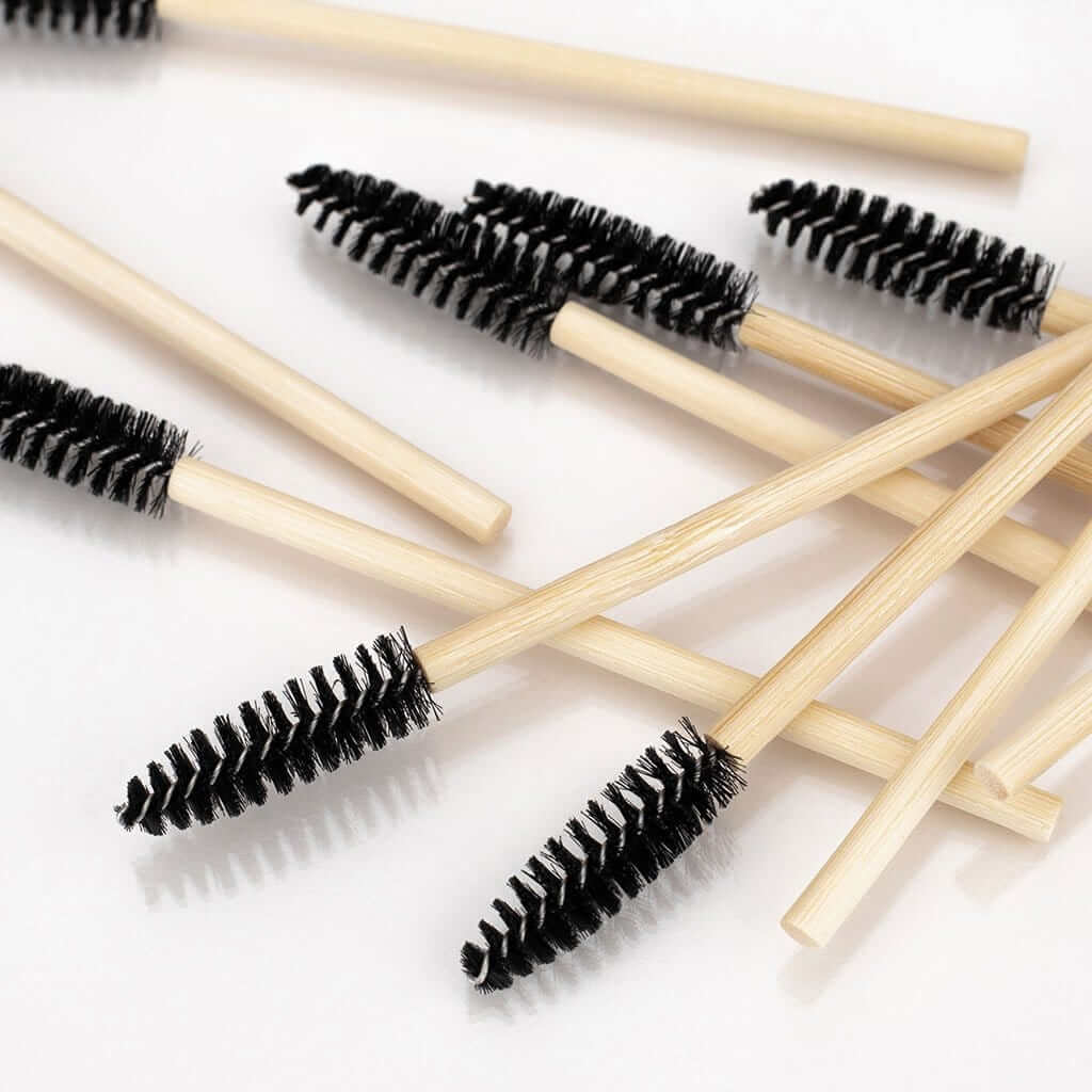 A pile of spoolies with a bamboo handle and black brush head, pointing in different directions